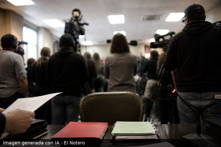 Sala de prensa o reunión institucional con una silla vacía, carpetas sobre una mesa y una mano sosteniendo un documento, en un ambiente tenso y anónimo.