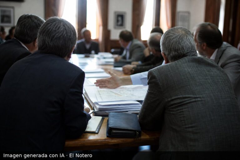 Reunión en una sala de una cámara empresaria con personas de espaldas alrededor de una mesa, documentos y mapas sobre la tenencia de tierras en primer plano.