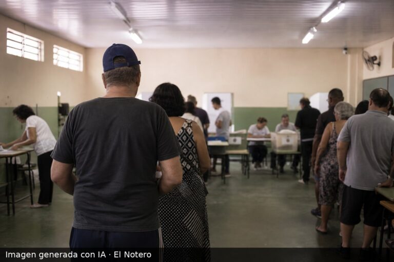 Personas anónimas de espaldas dentro de una escuela o centro de votación, con cabinas y urnas al fondo, en un ambiente electoral sobrio y desenfocado.