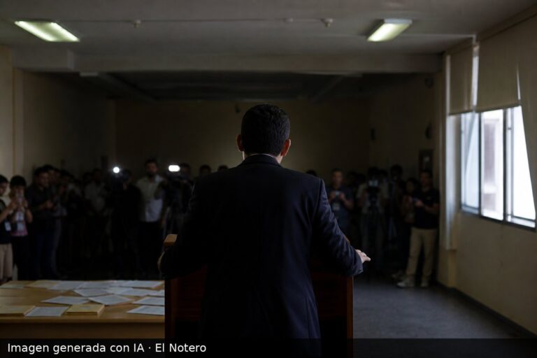 Interior de noche electoral con una figura de espaldas en un atril, gente desenfocada alrededor y papeles sobre una mesa, sin rostros visibles.