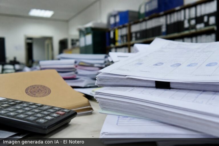 Una pila de expedientes judiciales y formularios de candidatura sobre un escritorio, con una carpeta sellada y una calculadora, en una oficina iluminada con luz fría.